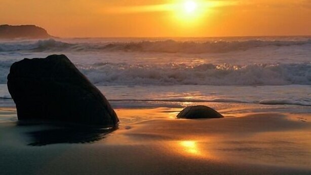 A beach scene with a rock in the foreground and waves in the background. - The Old School (Islay Island)