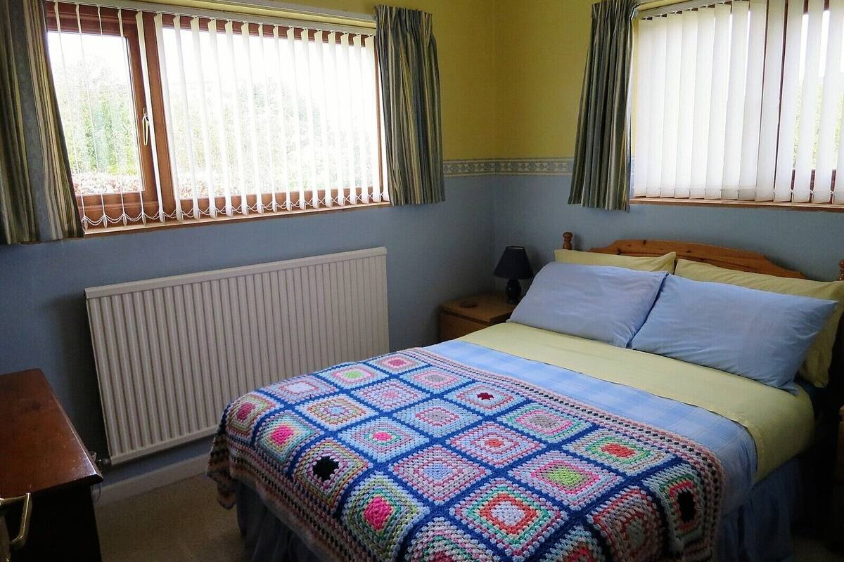 A bedroom with a bed, a nightstand, a lamp, and a radiator.
