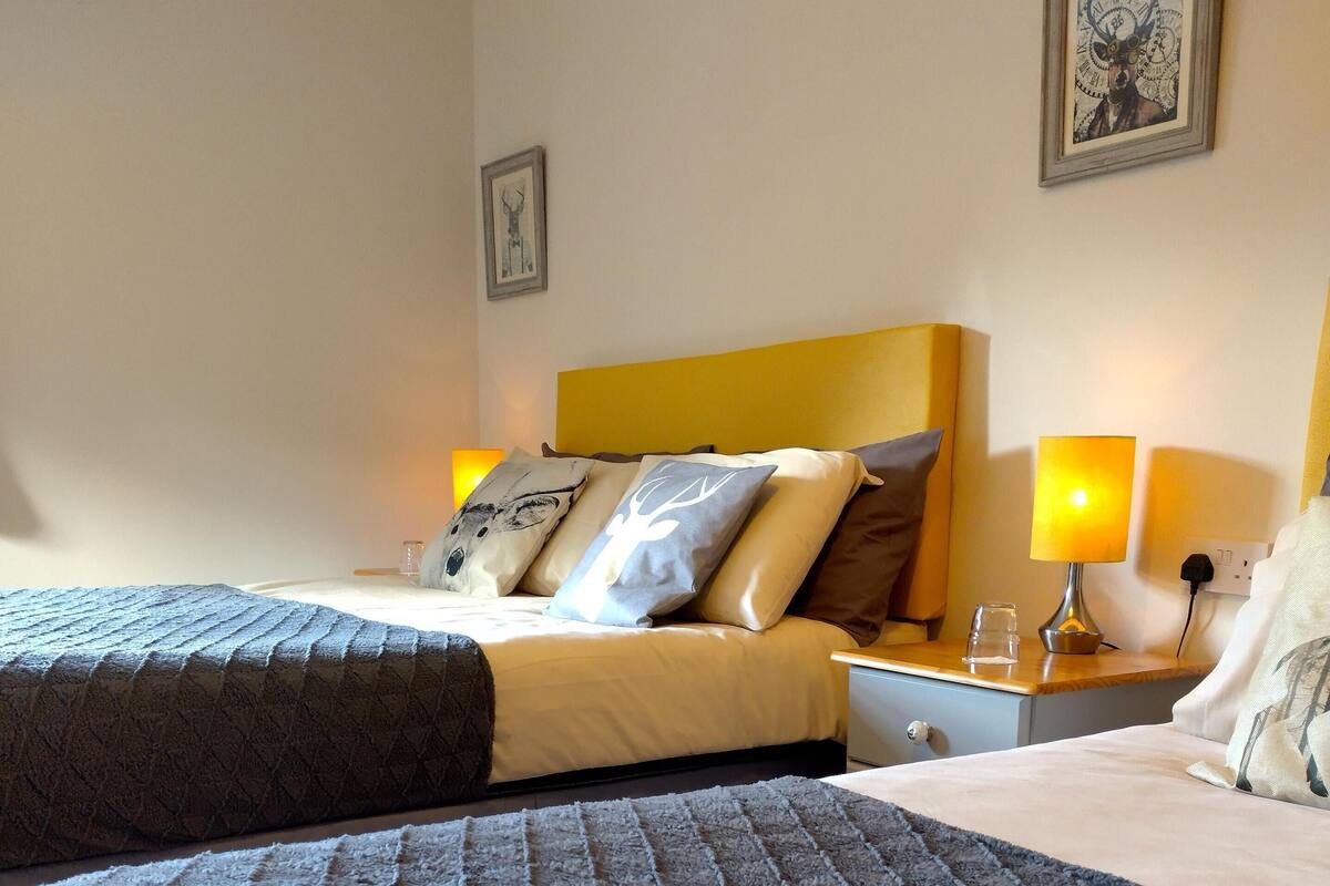 A hotel room with two beds, a headboard, bedside lamps, and a framed picture on the wall.