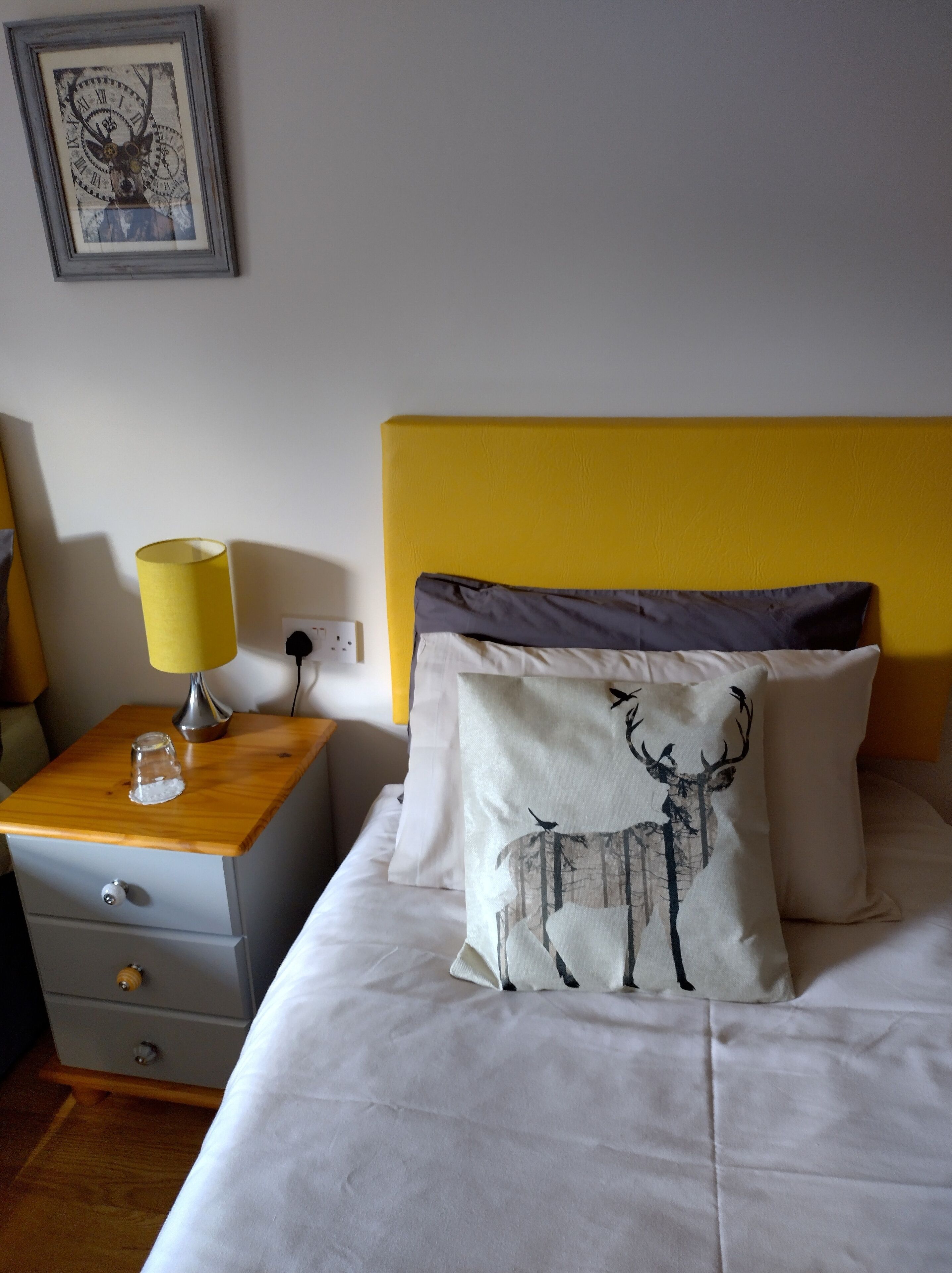 A hotel room with a bed, a nightstand, a lamp, and a wall clock.
