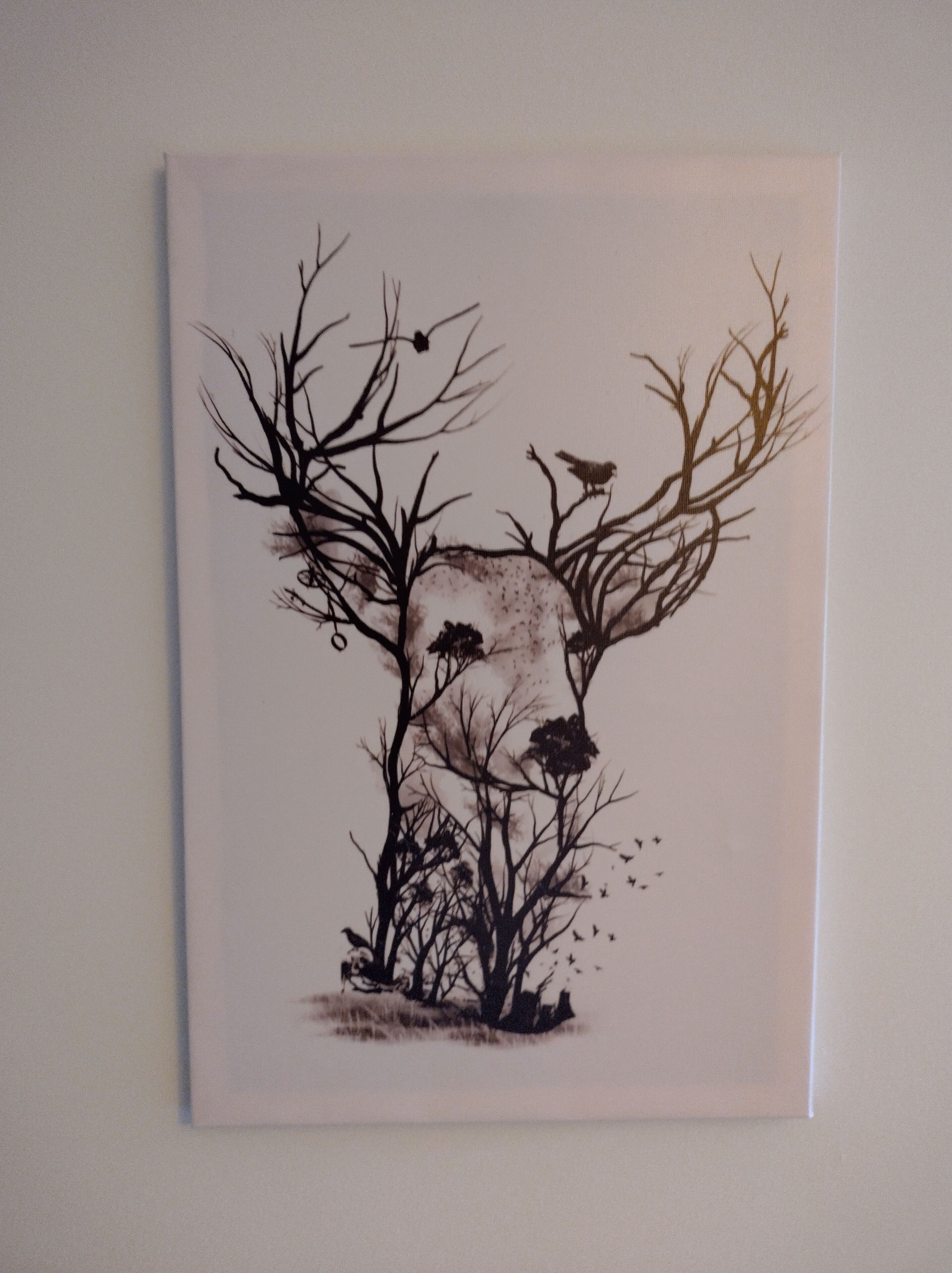 A wall-mounted artwork of a deer with antlers, surrounded by trees and birds.