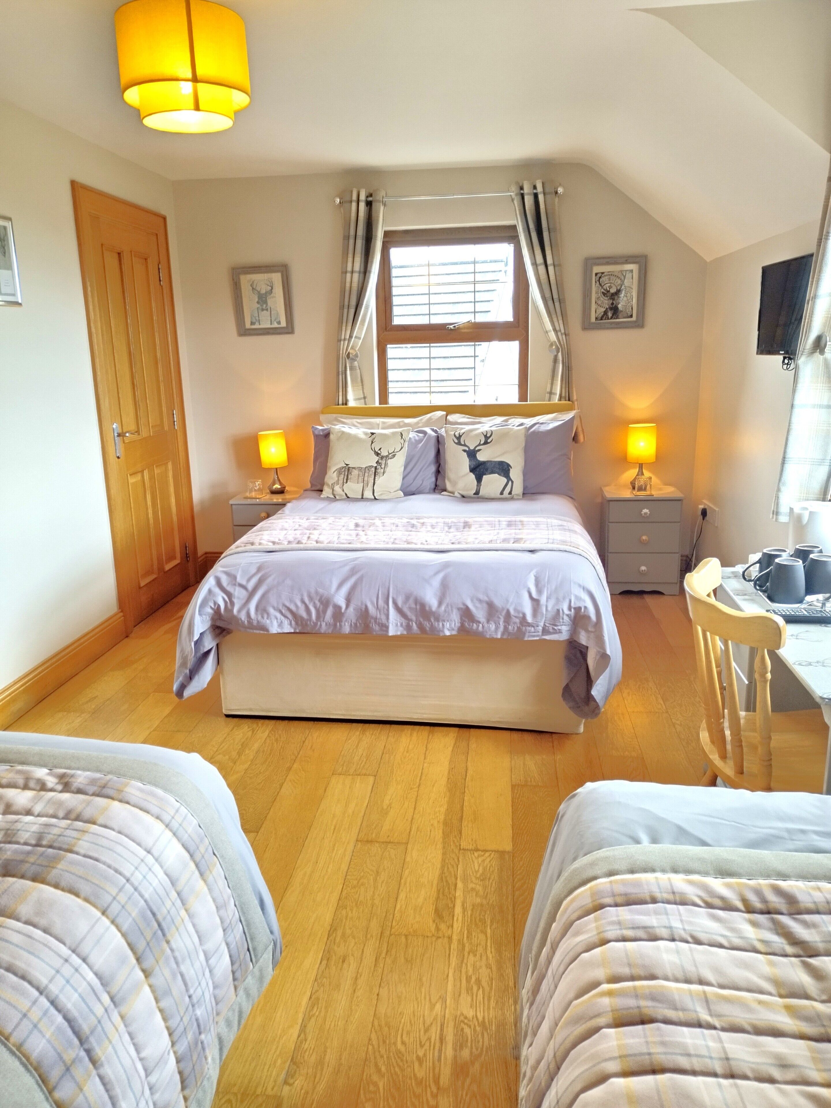 A bedroom with a large bed, two bedside tables with lamps, a wooden desk, and a chair.