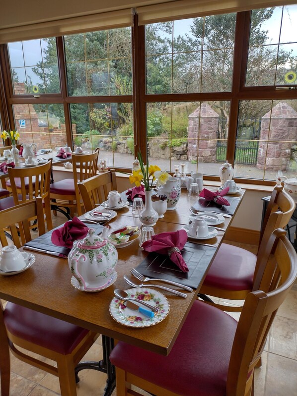 Comedor con una mesa dispuesta para cuatro personas, vajilla con estampado floral y sillas con asientos acolchados.