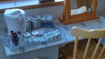 A desk with a mirror, a chair, and a small cabinet with drawers.
