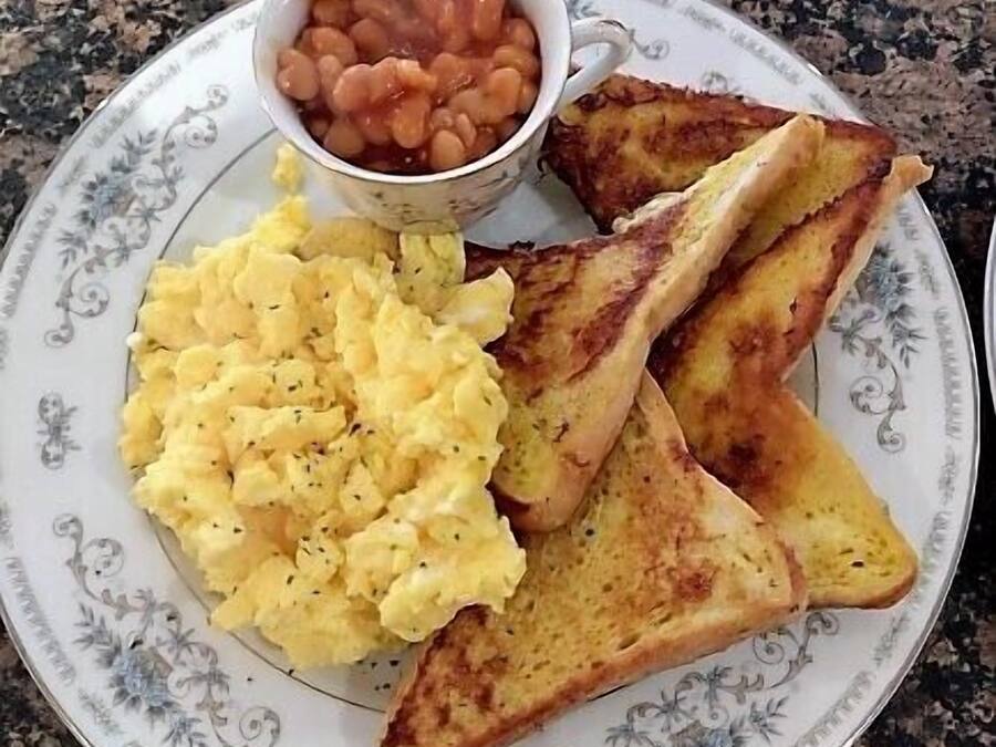 A plate with scrambled eggs, toast, and a small bowl of beans.