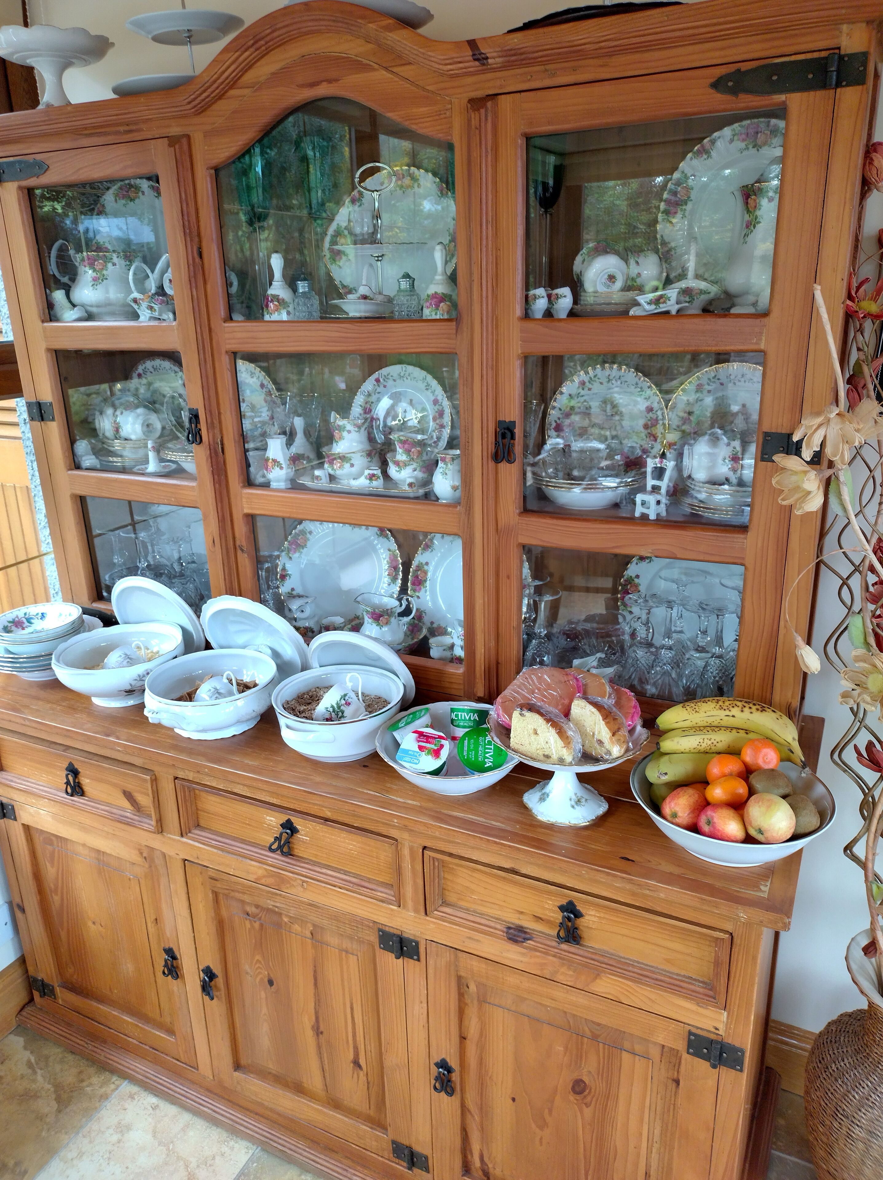 A wooden cabinet with glass doors displaying various white ceramic dishes and bowls.