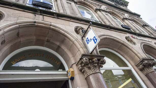 La façade d’un immeuble présente une entrée en arc surmontée de l’inscription « Résidence pour les clients de la banque ».