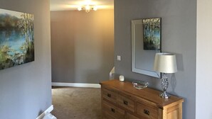Une chambre à coucher avec une commode en bois, un miroir et deux tableaux accrochés aux murs.
