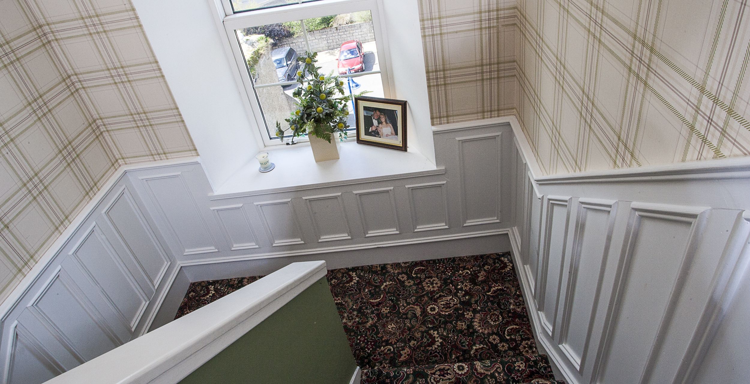 A staircase with a view of a parking area outside.