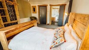 A wooden bed with a white mattress and colorful pillow, a wooden headboard, and a wooden ladder against a wall with patterned wallpaper. - The Inn at Kippen (Stirling)