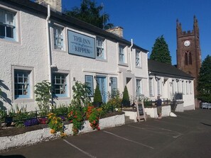 The Inn Kemp pub with a white facade, blue-framed windows, and a clock tower in the background.
