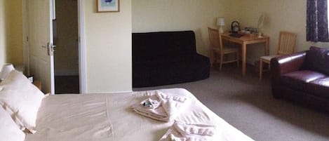 Una habitación de hotel con cama, escritorio, silla y sofá.