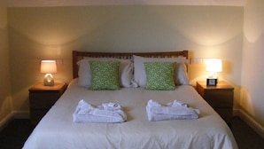 Una cama doble con dos almohadas, dos lámparas de noche y dos toallas dobladas sobre la cama.