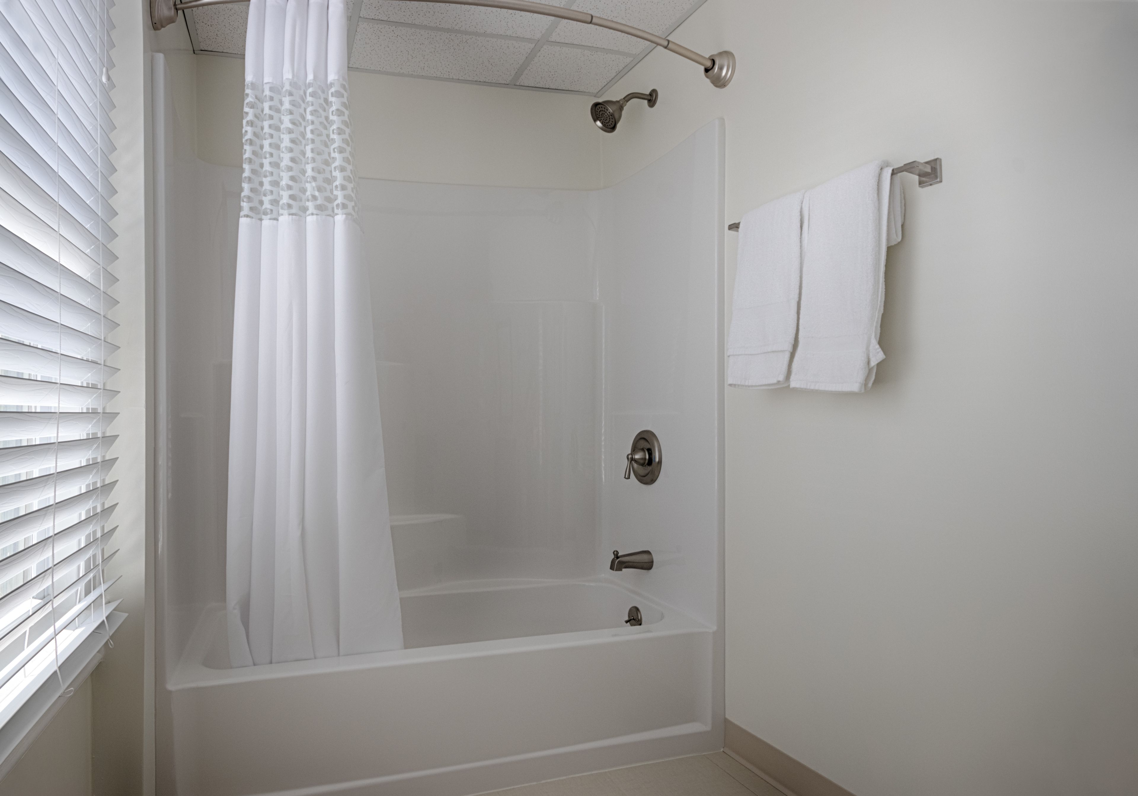 A bathroom with a bathtub, a shower curtain, and a towel rack.