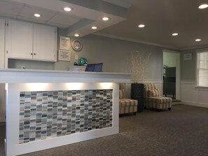A reception area with a tiled wall, a clock, and a sign with house rules. - The Wellington Hotel & Suites Oceanblock (Ocean City)
