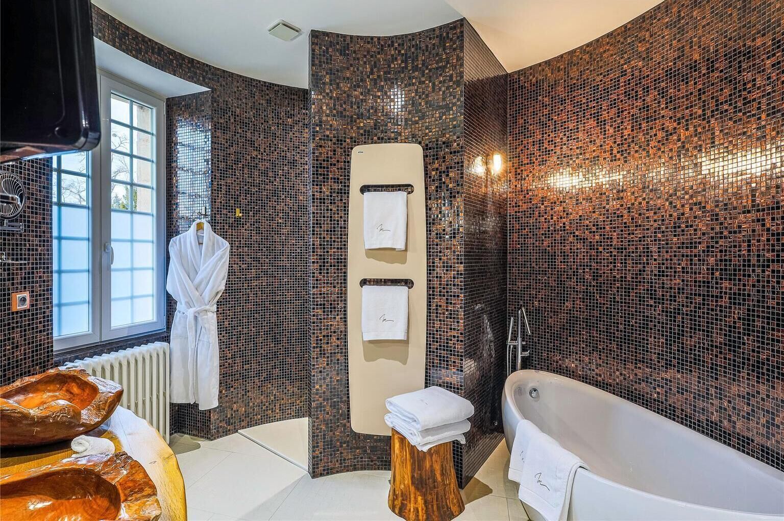 Une salle de bain moderne avec une baignoire, un meuble-lavabo en bois, un porte-serviettes et une fenêtre.