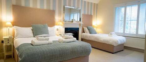 A hotel room with two beds, a fireplace, and a large window.