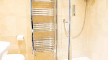 A bathroom with a glass-enclosed shower, a chrome towel rack, and a white toilet.