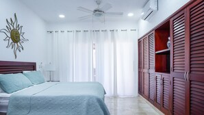 A bedroom with a bed, a ceiling fan, a wardrobe, and a sun decoration on the wall. - Magic Paradise by Bric (Playa del Carmen)