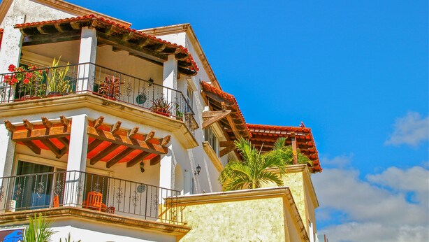 A multi-story building with balconies, red-tiled roofs, and potted plants. - Magic Paradise by Bric (Playa del Carmen)