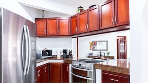 A kitchen with wooden cabinets, stainless steel appliances, and a granite countertop. - Magic Paradise by Bric (Playa del Carmen)