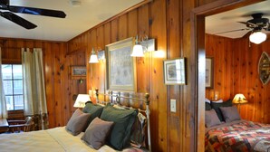 A wooden-paneled room with a large bed, a smaller bed, and a desk with a chair. - Moon River Cabins (Bellevue)