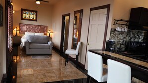 A modern kitchen with a black countertop, a stove, and a coffee machine. There is a dining area with a white table and chairs. The floor is tiled with a mix of light and dark tiles. - Moon River Cabins (Bellevue)