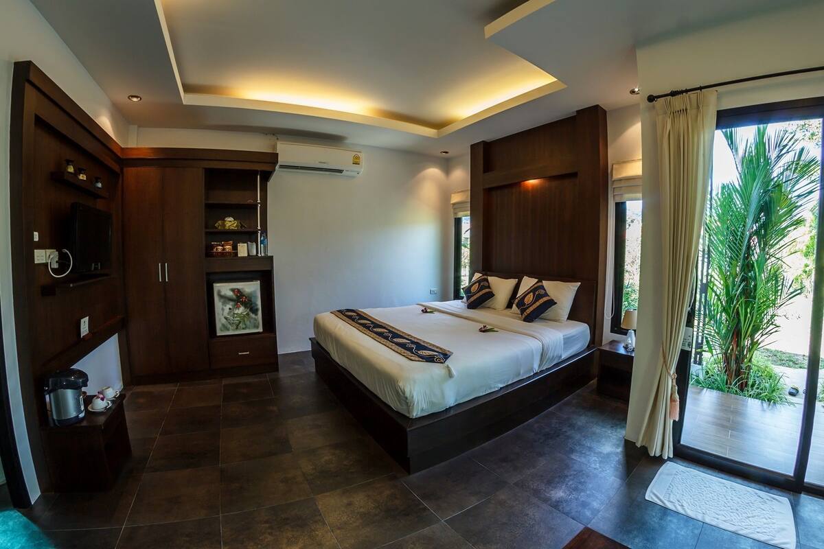 Un dormitorio moderno con una cama grande, armario empotrado y vistas a zonas verdes.