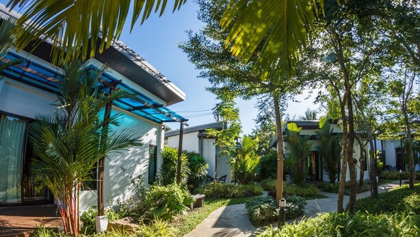 A modern house with a covered patio, surrounded by lush greenery and a clear sky. - Baan Armeen Cottage (Choeng Thale)