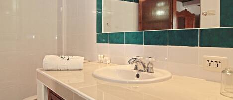A bathroom with a white sink, a mirror, and a toilet.