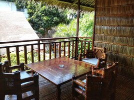 Una terraza de madera al aire libre con una mesa y sillas, rodeada de exuberante follaje.