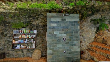 Relax in a serene outdoor space with a shower, handheld showerhead, and convenient toiletry shelf.