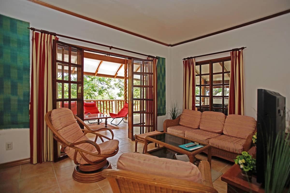 A living room with wicker furniture, a glass coffee table, and a television.