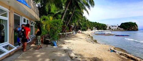 A beachside hotel with a view of the ocean and palm trees.