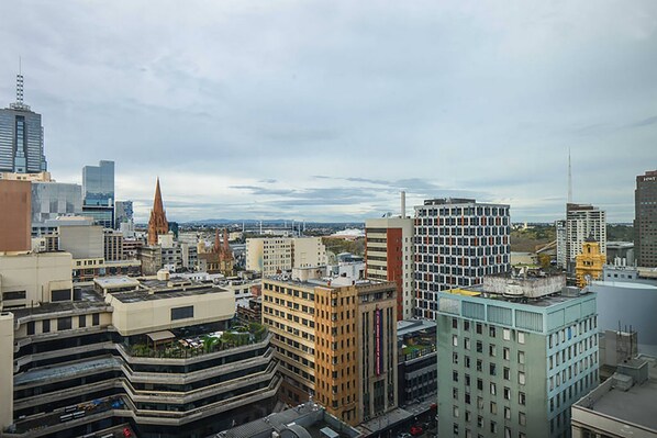 A cityscape with various buildings, including a prominent church spire and modern skyscrapers. - Anchor on Collins (Melbourne)