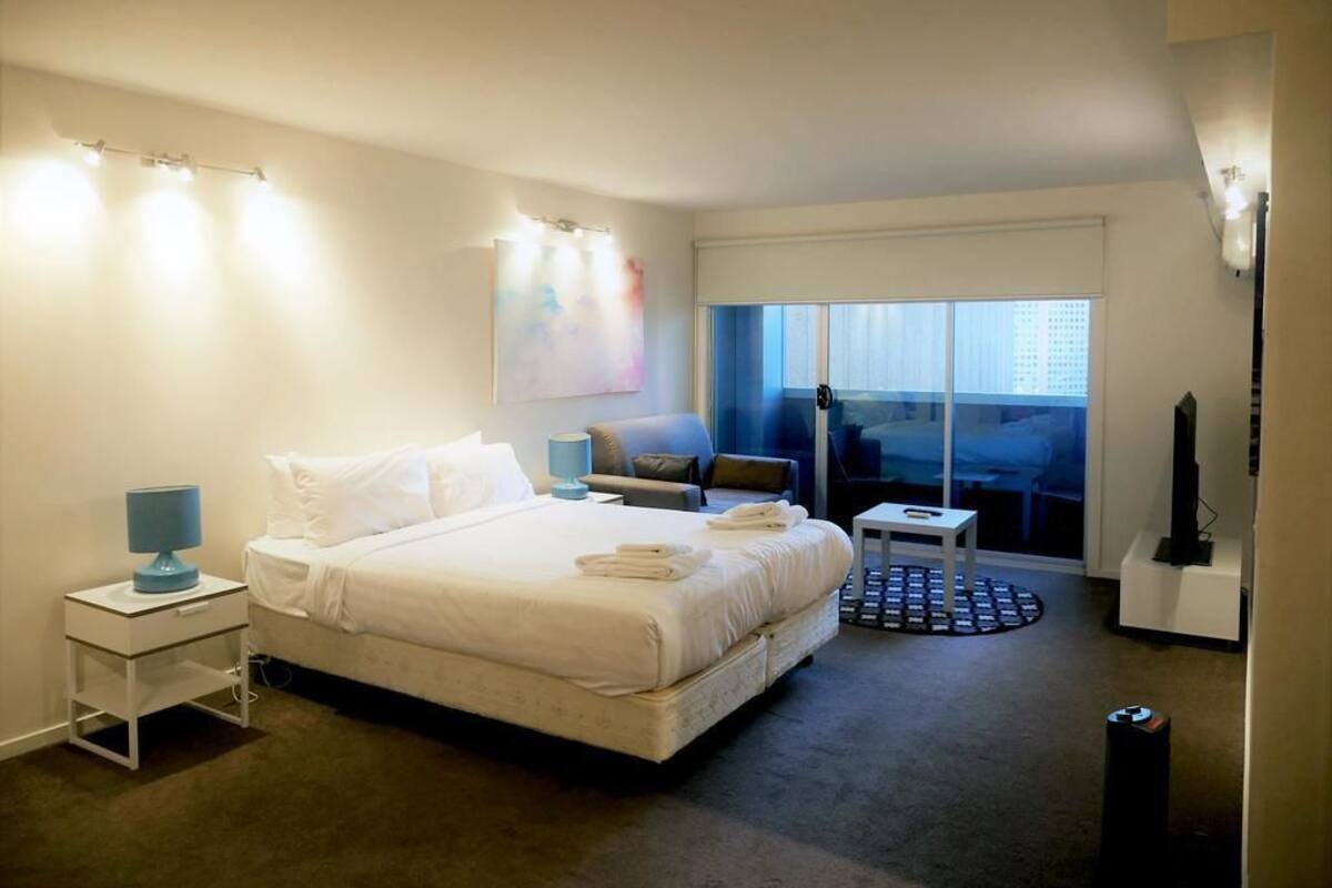 A hotel room with a large bed, bedside tables, a TV, and a window with a view.