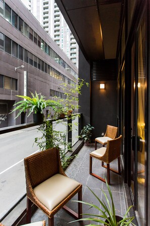 A balcony with wicker chairs and potted plants, overlooking a city street. - Anchor on Little Collins - Southern (Melbourne)
