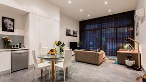 A modern living space with a dining area, sofa, and a large window with curtains. - Anchor on Little Collins - Southern (Melbourne)