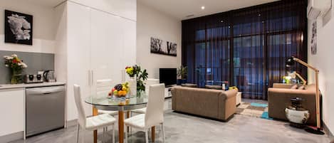 A modern living space with a dining area, sofa, and a large window with curtains.