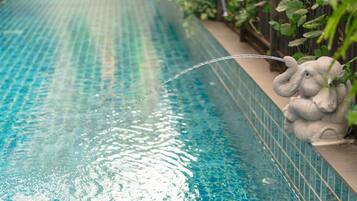 Una piscina amb aigua cristal·lina blava i una estàtua decorativa d'un elefant al vorell.