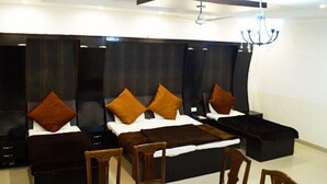 Een moderne hotelkamer met een groot bed, meerdere kussens, een donker hoofdeinde, een kroonluchter en een klein houten tafeltje.