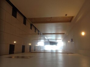 A spacious corridor with tiled walls and a wooden ceiling, leading to a bright exit. - Baan Romdee (Pak Kret)