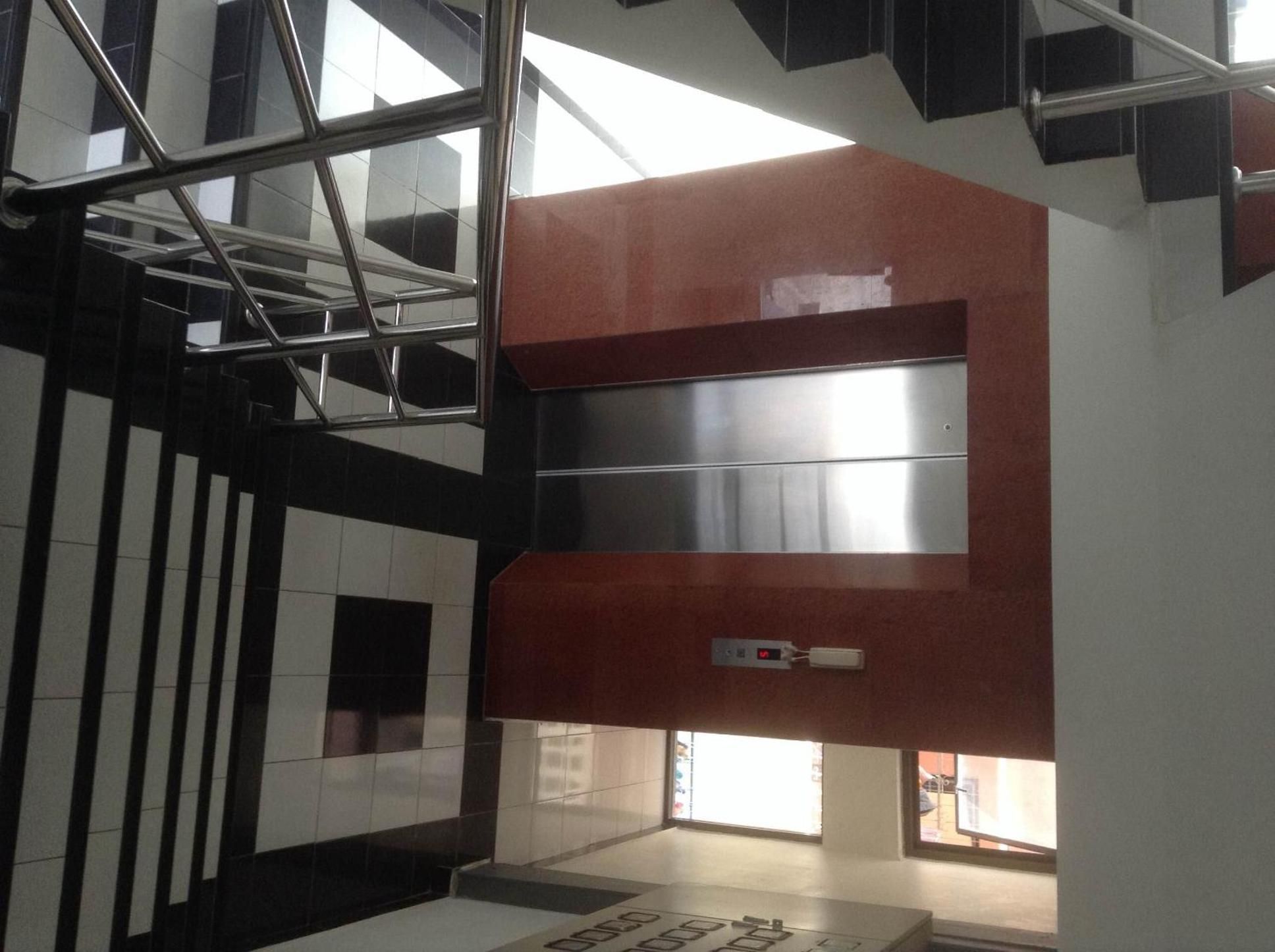 A modern interior with a staircase, metal railings, and a patterned floor.