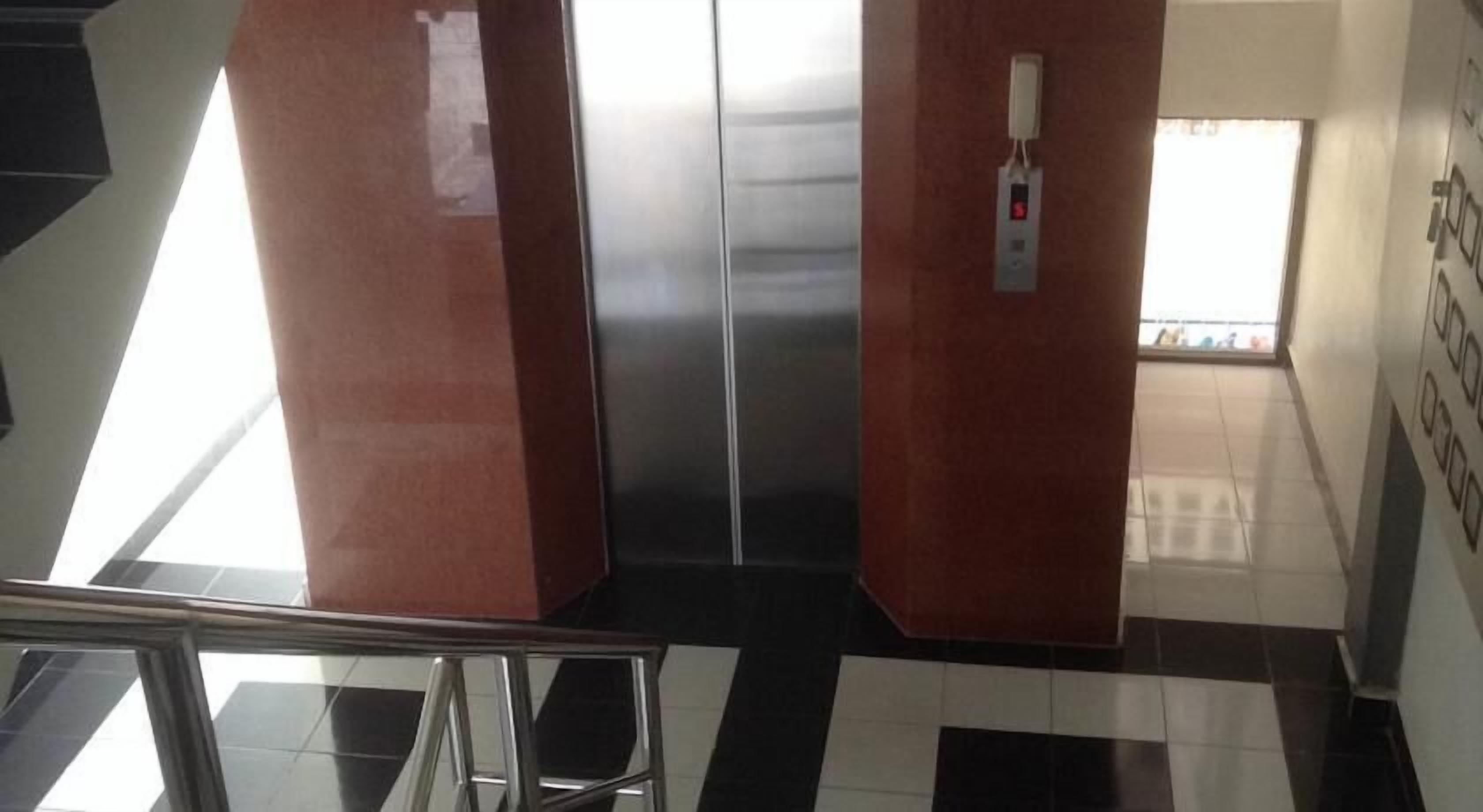 Un ascensor con puertas metálicas y un panel de control con un botón rojo.