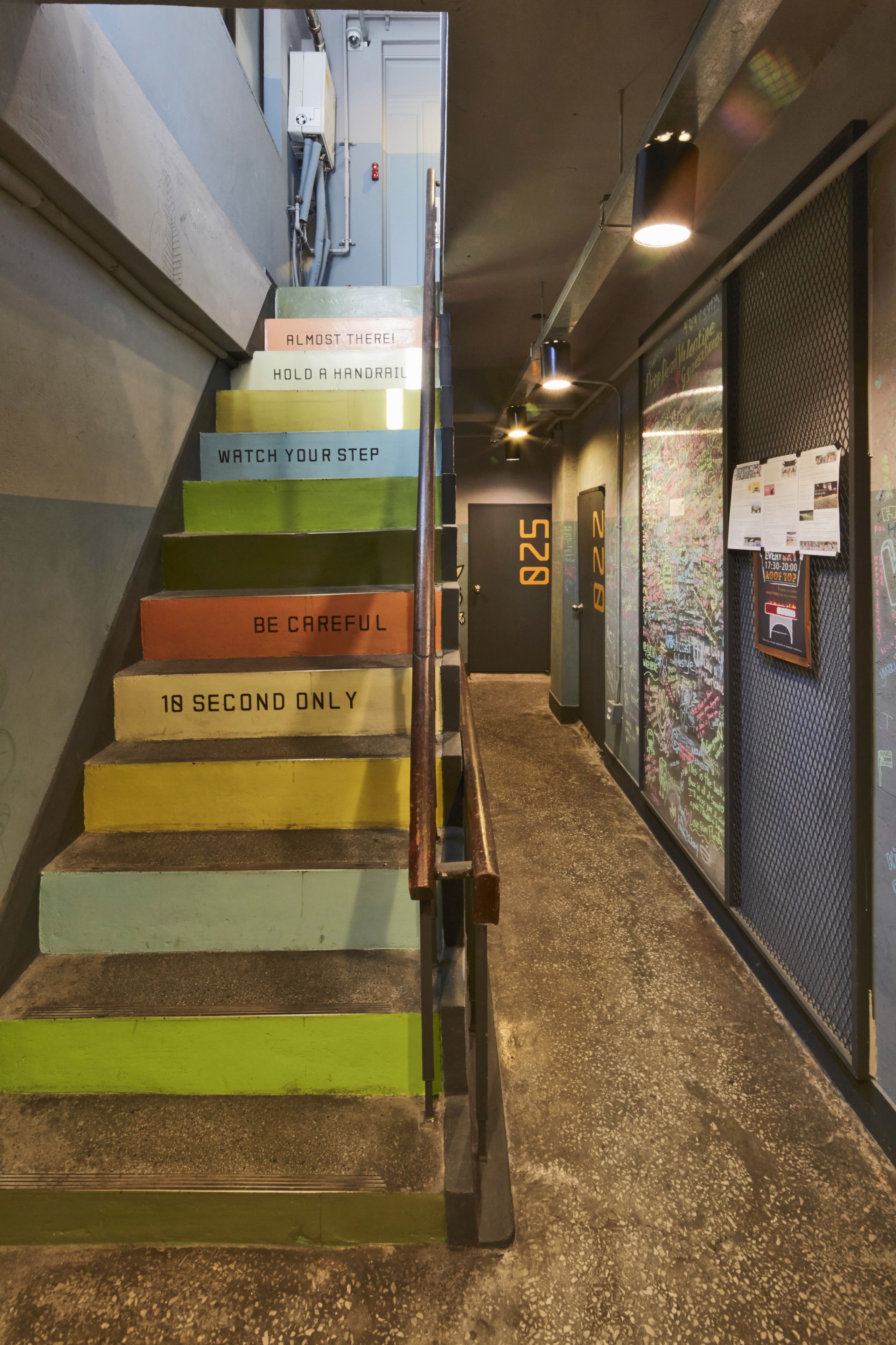 Una escalera con frases motivacionales en cada peldaño y un pasillo con una puerta marcada con el número 825.