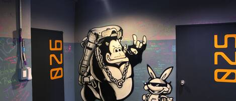 A wall with graffiti art, including a large figure and a smaller character, and the number 928 on the doors.