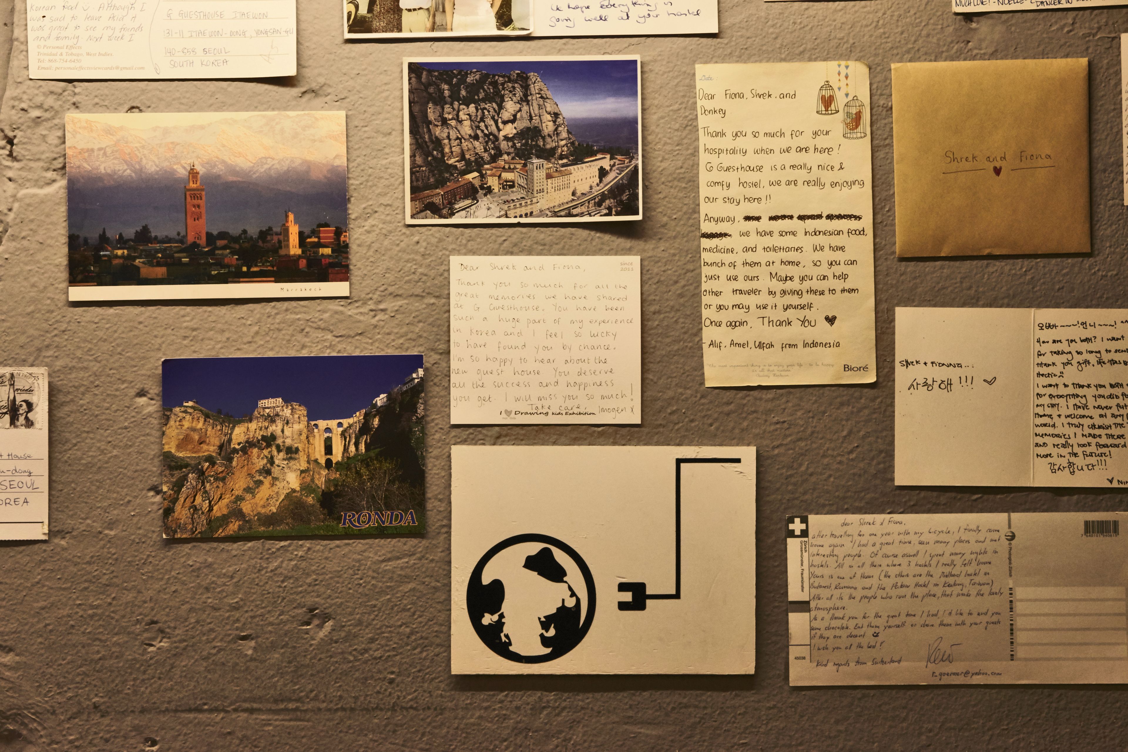 Un mur orné de diverses cartes postales, de lettres et d’un globe terrestre.
