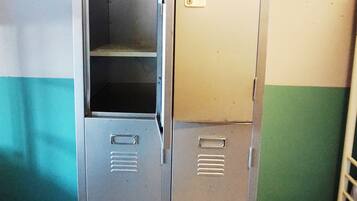 A set of metal lockers with a handle and a small shelf, against a wall with a teal and white color scheme.