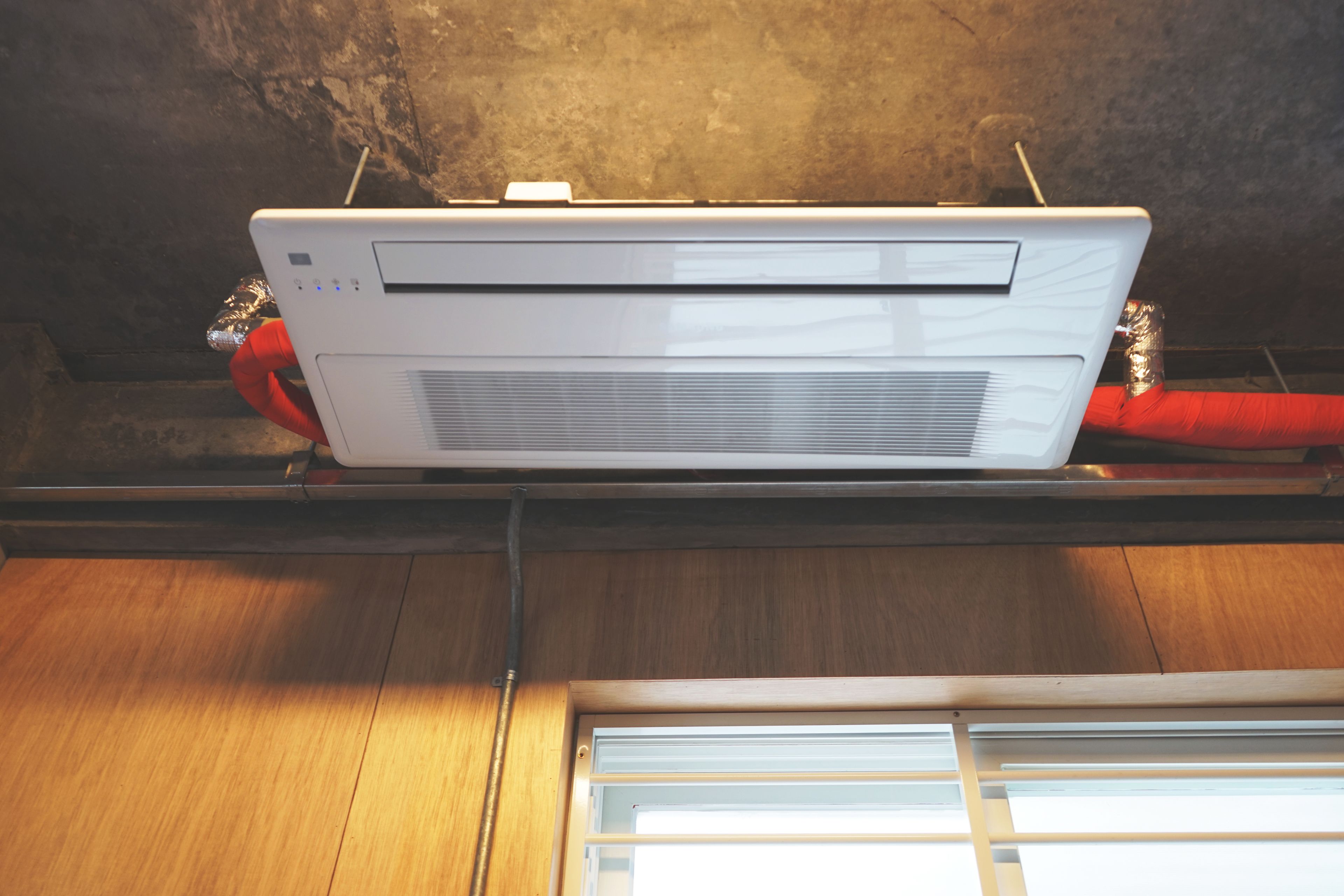 A white air conditioning unit mounted on a wooden beam with a metal frame.