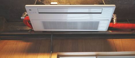 A white air conditioning unit mounted on a wooden beam with a metal frame.